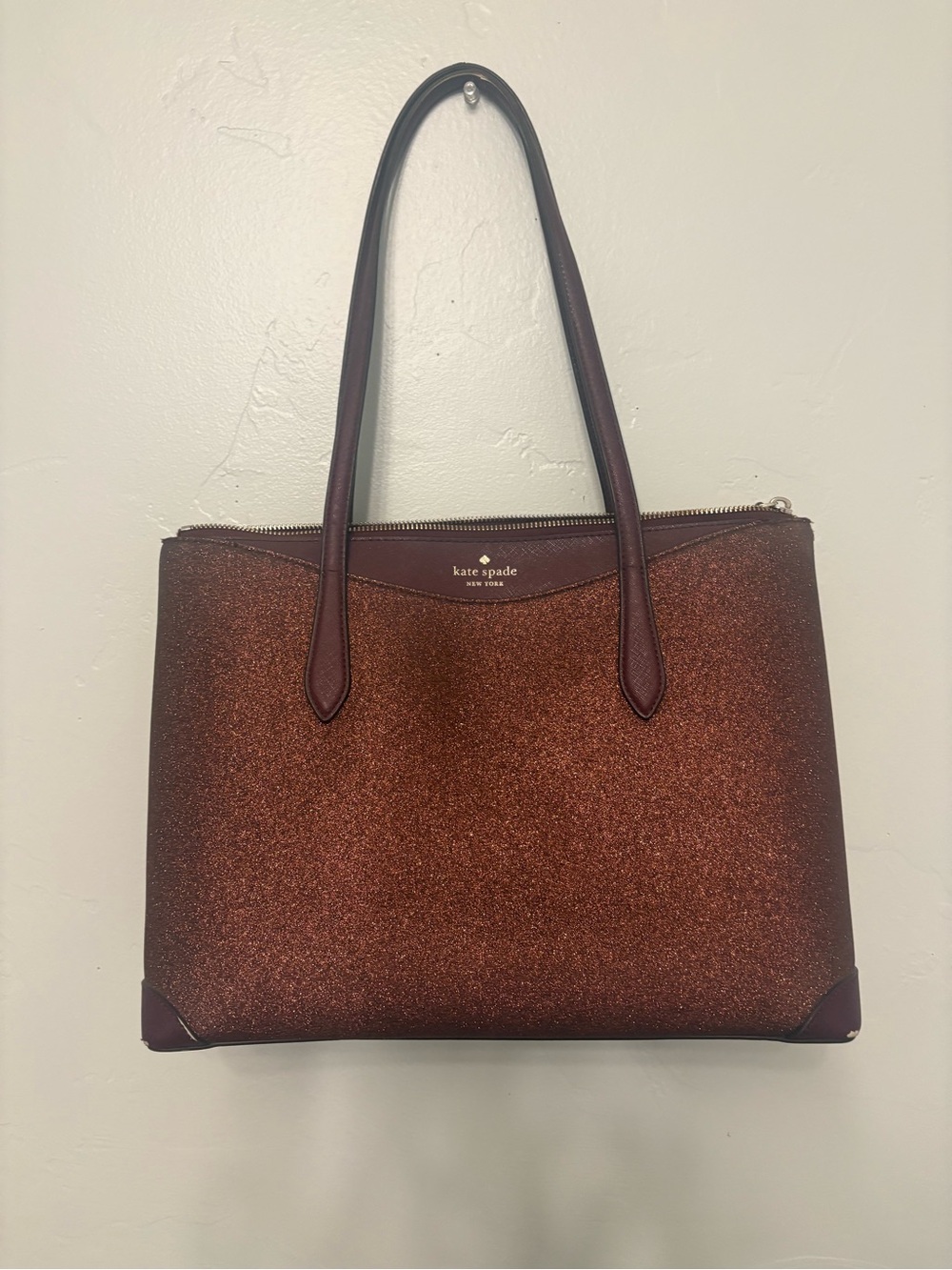 Kate Spade New York glitter tote bag in a deep burgundy shade.
